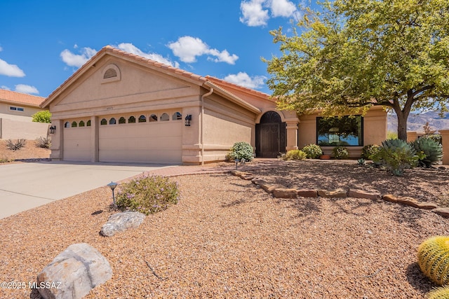 view of front of home featuring an attached garage, a tiled roof, concrete driveway, and stucco siding
