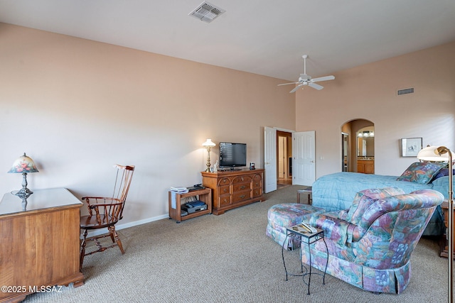 carpeted bedroom featuring arched walkways, baseboards, visible vents, and a towering ceiling