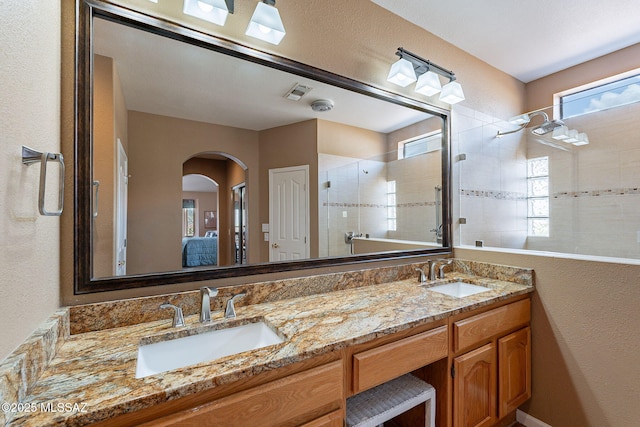 ensuite bathroom featuring a sink, visible vents, a stall shower, and a healthy amount of sunlight