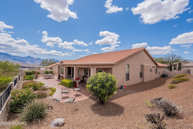 rear view of house with central air condition unit, stucco siding, a patio area, a fenced backyard, and a tile roof