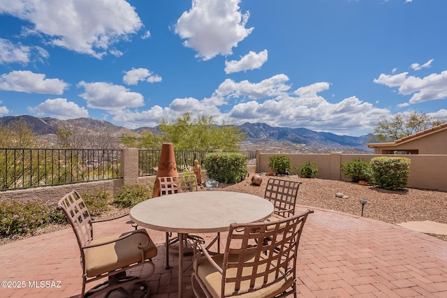 view of patio featuring a mountain view, outdoor dining space, and fence