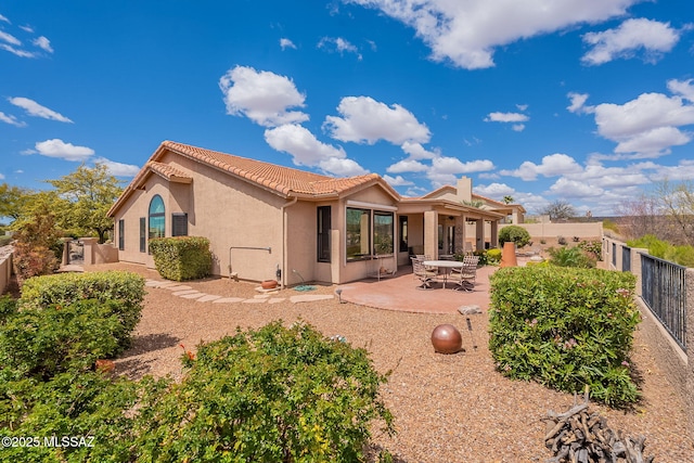 back of house with a tiled roof, a fenced backyard, a patio, and stucco siding