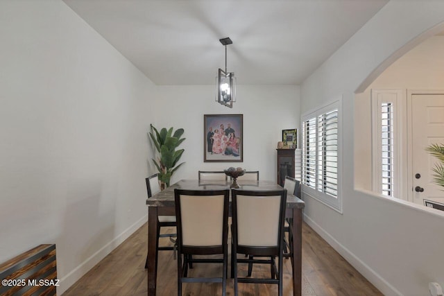 dining area with arched walkways, wood finished floors, and baseboards