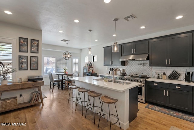 kitchen featuring visible vents, stainless steel range, under cabinet range hood, and a sink