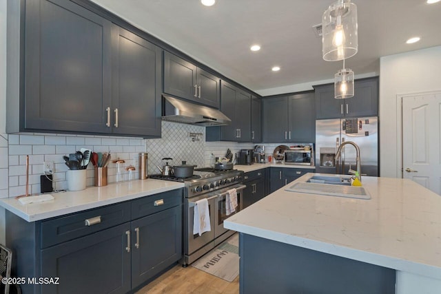 kitchen with stainless steel appliances, under cabinet range hood, light wood-style flooring, backsplash, and hanging light fixtures