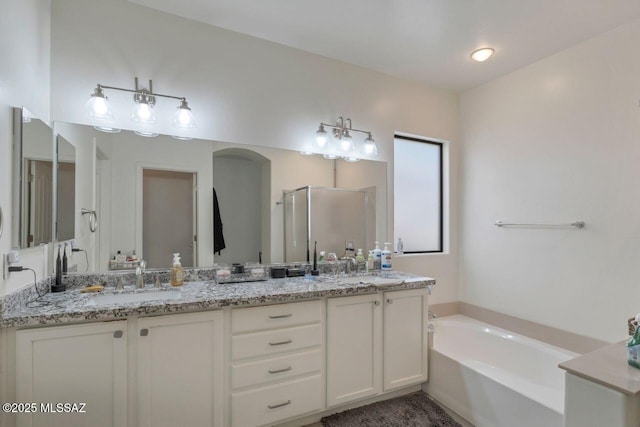 full bathroom featuring double vanity, a garden tub, and a sink