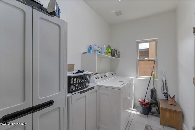 laundry area featuring laundry area, light tile patterned floors, washing machine and dryer, baseboards, and visible vents