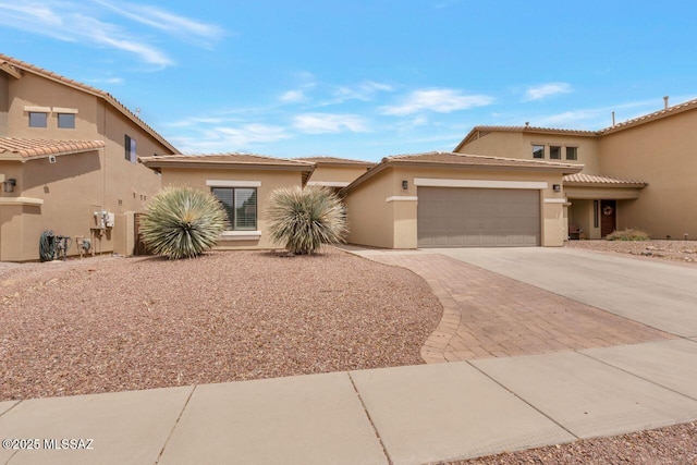view of front facade featuring a tiled roof, stucco siding, concrete driveway, and an attached garage