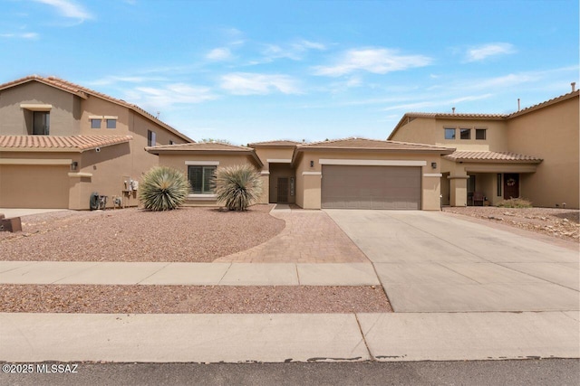 view of front of property featuring a garage, a tile roof, stucco siding, and driveway
