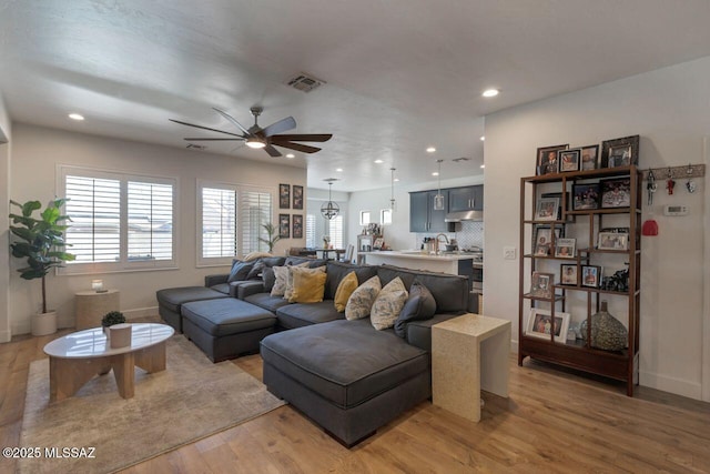living room featuring light wood finished floors, recessed lighting, a ceiling fan, visible vents, and baseboards