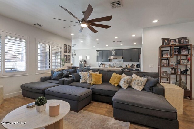 living room featuring visible vents, a ceiling fan, and light wood finished floors