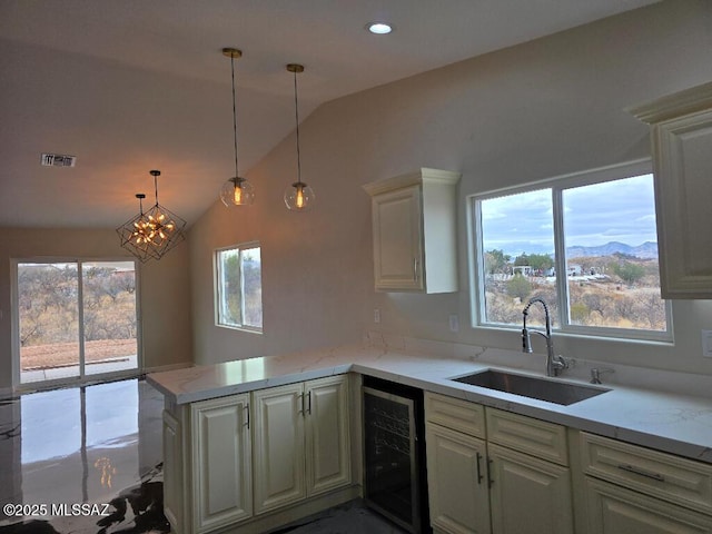 kitchen with a peninsula, visible vents, vaulted ceiling, a sink, and wine cooler