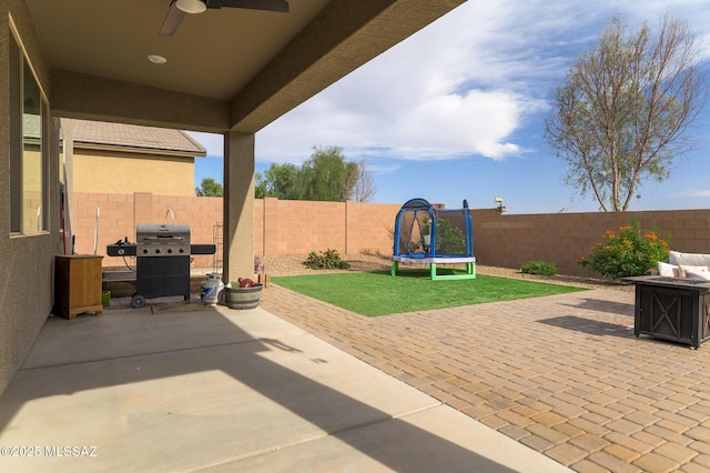 3295 W Sunlit Peak Dr, Tucson, AZ 85742 - view of patio featuring a trampoline, a fire pit, grilling area, a fenced backyard, and ceiling fan
