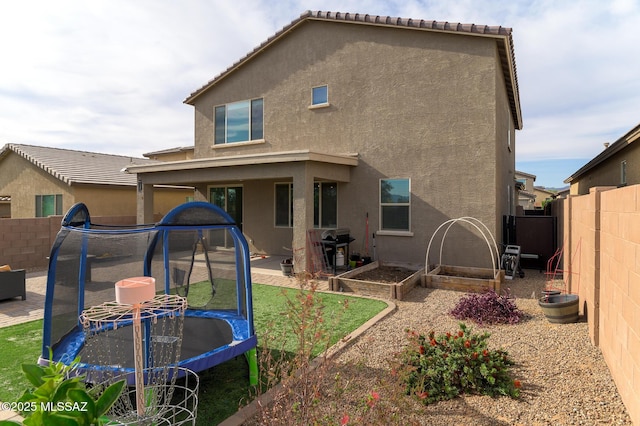 3295 W Sunlit Peak Dr, Tucson, AZ 85742 - rear view of house with a trampoline, a patio area, a fenced backyard, and stucco siding