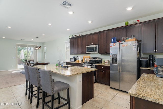 3295 W Sunlit Peak Dr, Tucson, AZ 85742 - kitchen featuring a kitchen breakfast bar, light tile patterned floors, visible vents, stainless steel appliances, and a sink