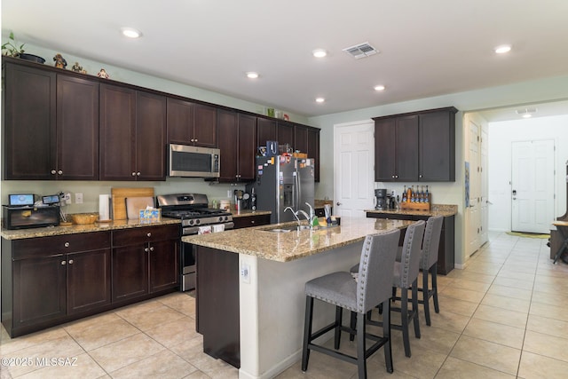 3295 W Sunlit Peak Dr, Tucson, AZ 85742 - kitchen with light tile patterned floors, a kitchen bar, visible vents, a sink, and stainless steel appliances