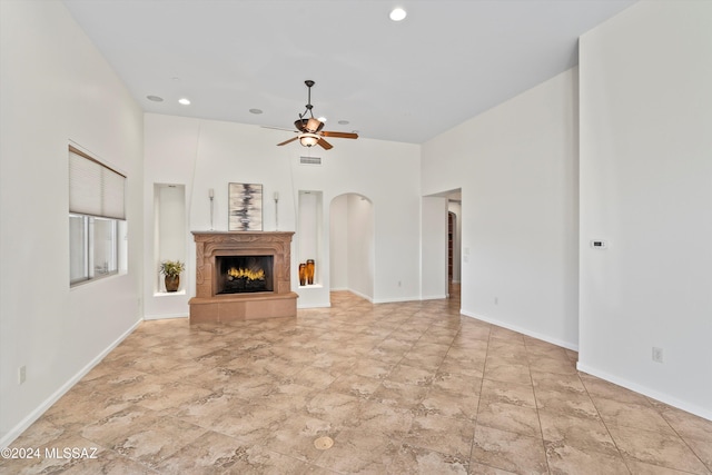 unfurnished living room featuring arched walkways, a ceiling fan, visible vents, recessed lighting, and a tiled fireplace