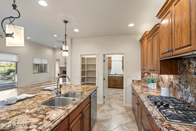 kitchen with stone countertops, brown cabinets, appliances with stainless steel finishes, and a sink