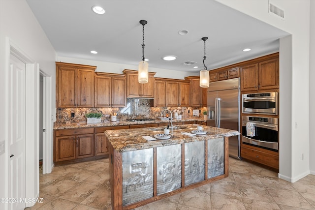 kitchen with brown cabinetry, stainless steel built in refrigerator, stone counters, visible vents, and decorative backsplash