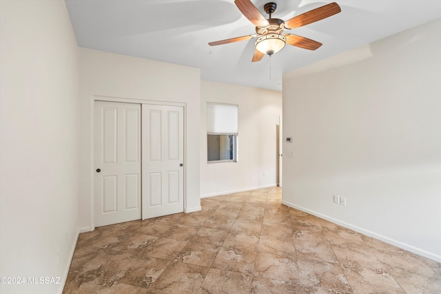 unfurnished room with ceiling fan, stone finish floor, and baseboards