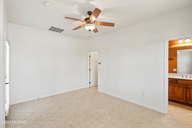 unfurnished bedroom featuring light tile patterned floors, connected bathroom, visible vents, a sink, and baseboards