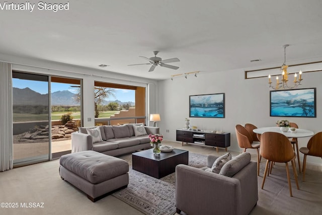 living room with ceiling fan with notable chandelier, rail lighting, and visible vents