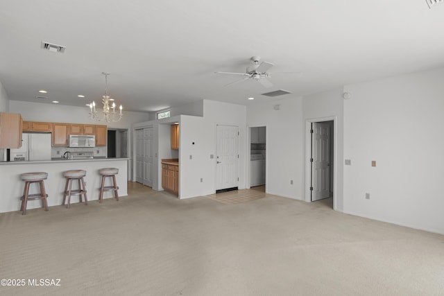 living area with ceiling fan with notable chandelier, visible vents, recessed lighting, light carpet, and washer / dryer