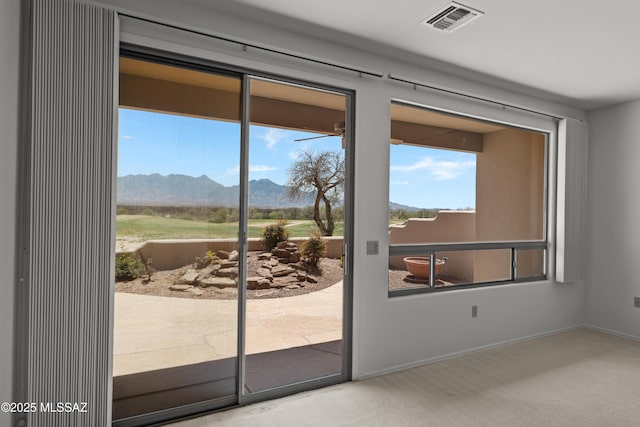 doorway to outside with a mountain view, carpet flooring, visible vents, and a wealth of natural light