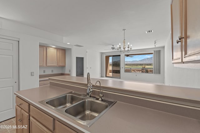kitchen with an inviting chandelier, light countertops, visible vents, pendant lighting, and a sink