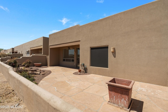 rear view of house with a patio, stucco siding, and fence