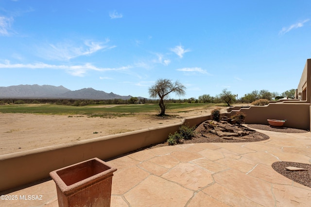 view of patio with a mountain view and fence