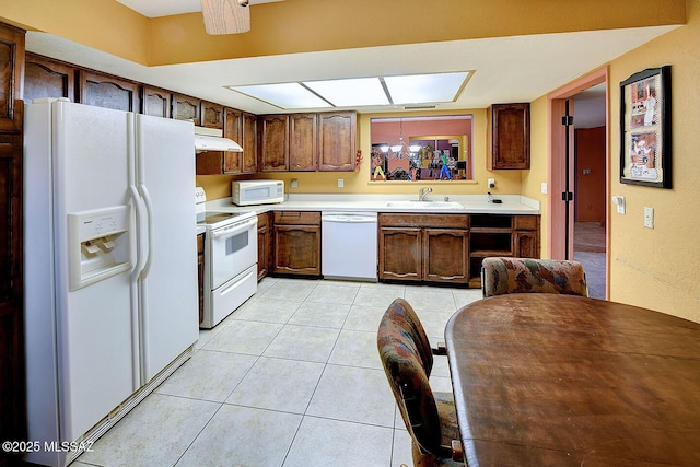 kitchen featuring white appliances, light countertops, light tile patterned flooring, under cabinet range hood, and a sink