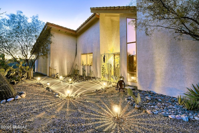 back of property featuring a tile roof and stucco siding