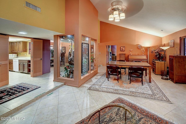 dining space with high vaulted ceiling, light tile patterned floors, and visible vents