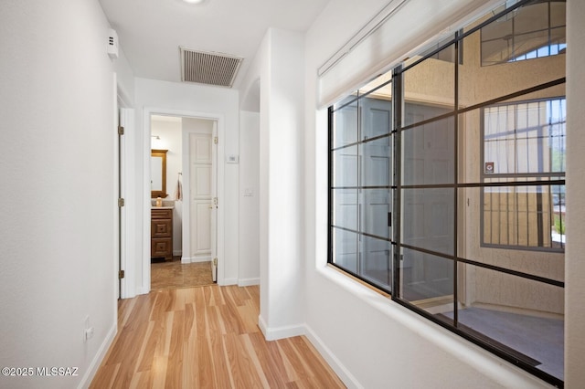 hall featuring visible vents, baseboards, and light wood-style flooring