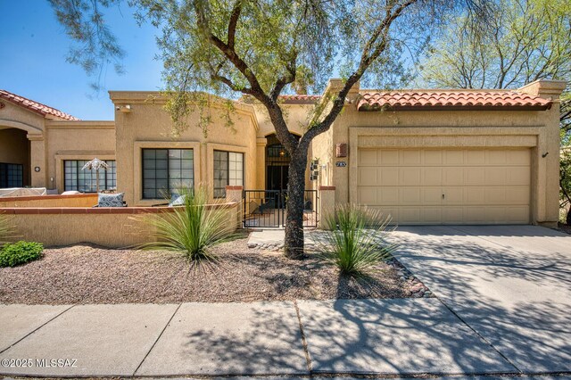 mediterranean / spanish house featuring a tiled roof, a fenced front yard, stucco siding, an attached garage, and concrete driveway