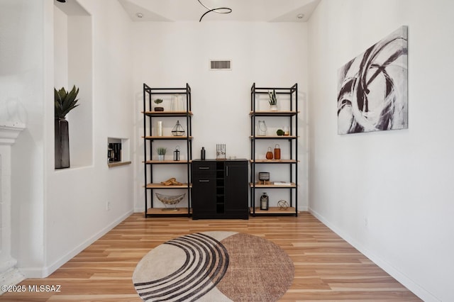 hall featuring visible vents, baseboards, and wood finished floors