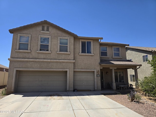 traditional-style house featuring concrete driveway, an attached garage, a tile roof, and stucco siding