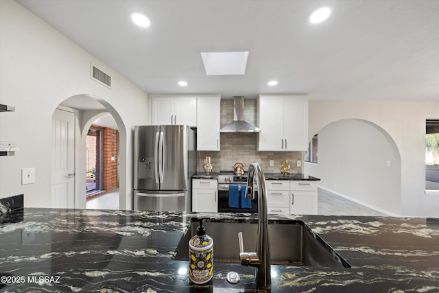 kitchen with visible vents, appliances with stainless steel finishes, white cabinetry, and wall chimney exhaust hood