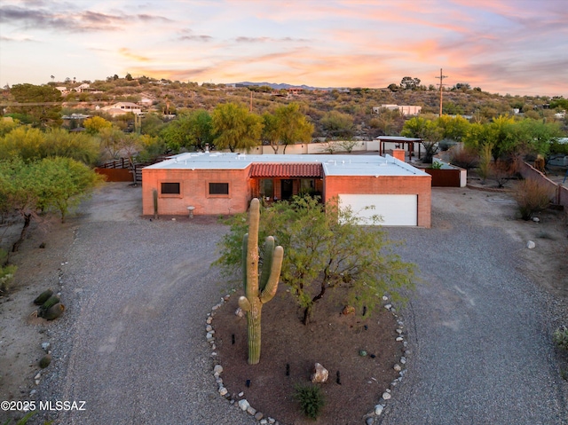 view of front of home with fence and gravel driveway