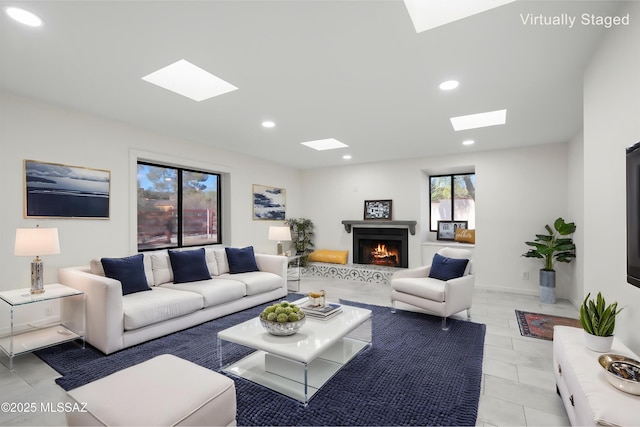 living room featuring a skylight, recessed lighting, a warm lit fireplace, and light tile patterned flooring