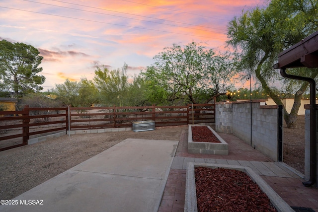 yard at dusk featuring a garden, a fenced backyard, and a patio area
