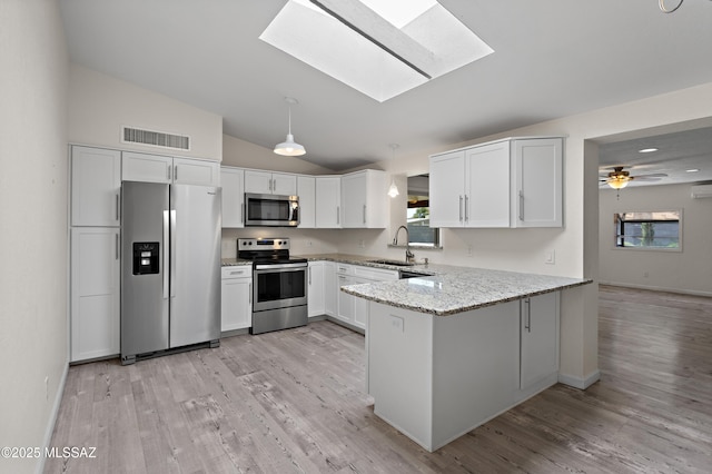 kitchen featuring visible vents, a sink, appliances with stainless steel finishes, light wood-style floors, and a peninsula