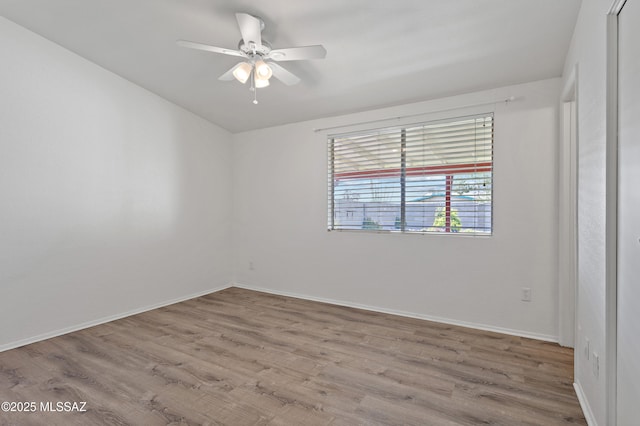 spare room with baseboards, wood finished floors, and ceiling fan