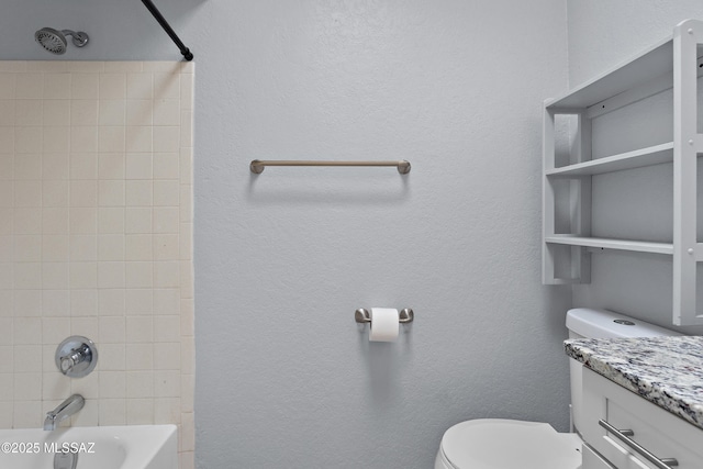 bathroom with a textured wall, vanity,  shower combination, and toilet