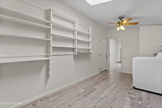 laundry room with laundry area, a skylight, wood finished floors, washer / dryer, and baseboards