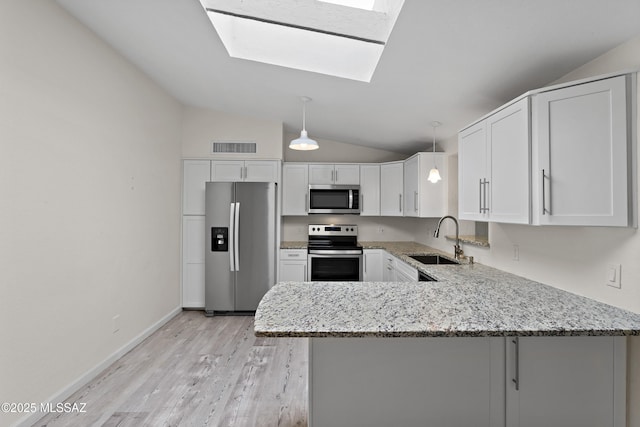kitchen with white cabinets, a sink, a peninsula, light stone countertops, and stainless steel appliances