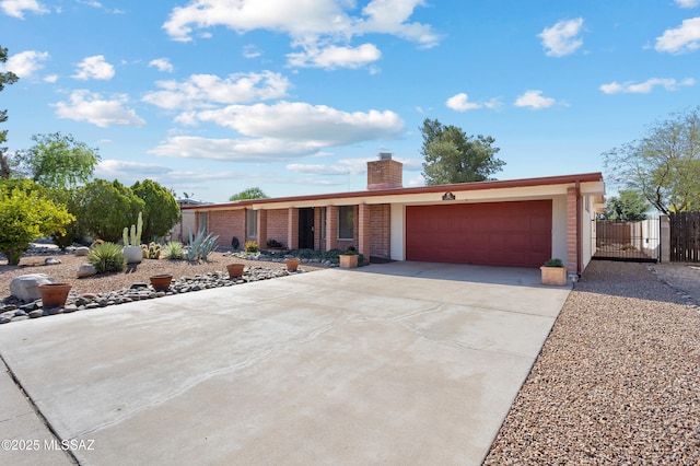 view of front of house with fence, a gate, an attached garage, a chimney, and driveway