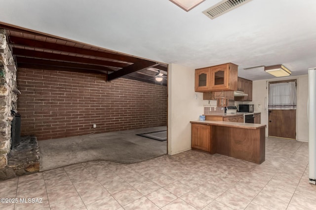 423 E Hadley St, Tucson, AZ 85705 - kitchen featuring brown cabinets, light countertops, brick wall, and range