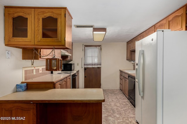 423 E Hadley St, Tucson, AZ 85705 - kitchen with black appliances, visible vents, under cabinet range hood, light countertops, and glass insert cabinets